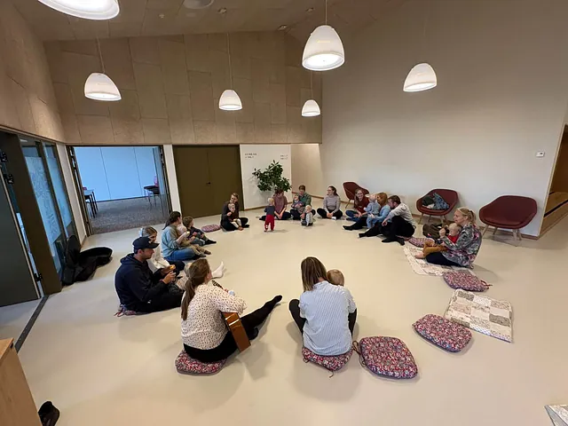 Forældre der sidder i rundkreds med deres børn i armene